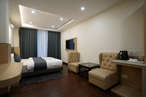 a hotel room with a bed and a chair at Hotel Apple Inn by Eastern Hospitality in Gangtok