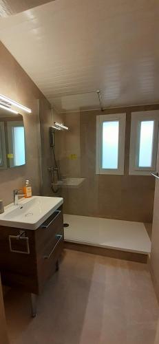 La salle de bains est pourvue d'un lavabo, d'une douche et de 2 fenêtres. dans l'établissement VILLAGE OCCITAN Magnifique T3 mezzanine proche plage Roquille Clim et Wifi Cap d'Agde, au Cap d'Agde