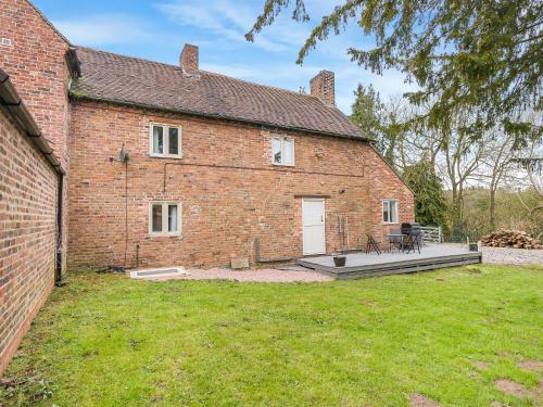 un antiguo edificio de ladrillo con terraza en el patio en 3 Bedroom Country Cottage with Private Garden, en Shifnal