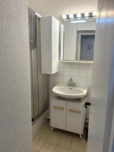 une salle de bain blanche avec un lavabo et un miroir dans l'établissement appartement au bord de l'océan, à Saint-Hilaire-de-Riez