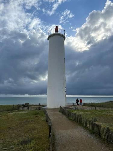 Un phare blanc avec deux personnes debout en haut dans l'établissement appartement au bord de l'océan, à Saint-Hilaire-de-Riez