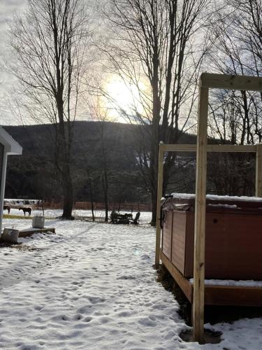 a snow covered yard with a wooden gate and trees at The Cabins at Walnut Grove-minutes from Hunter and Windham in Ashland