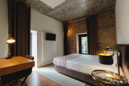 a bedroom with a bed and a table and a desk at Borralha Hotel, Restaurante & Spa in Vila Real