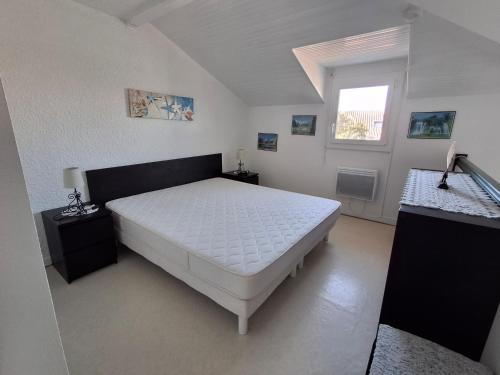 une chambre avec un lit blanc et une fenêtre dans l'établissement Villa patio à 200 m de la plage à Capbreton, à Capbreton