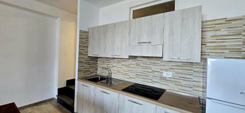 a kitchen with white cabinets and a sink and a refrigerator at Residenza Albachiara in Castelsardo