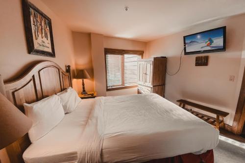 ein Schlafzimmer mit einem Bett und einem Fernseher an der Wand in der Unterkunft Red Hawk Lodge 2222 by SummitCove Lodging in Keystone