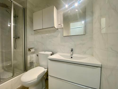 une salle de bain blanche avec des toilettes et un lavabo dans l'établissement Famille & Farniente - Terrasse verdoyante au couchant, à La Grande Motte