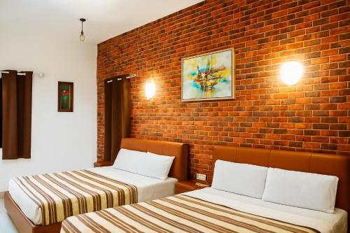 two beds in a room with a brick wall at Welcome Inn in Grand Baie