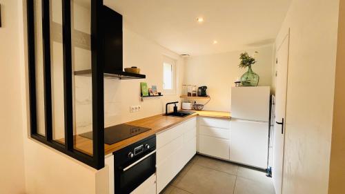 une cuisine avec des armoires blanches et un réfrigérateur blanc dans l'établissement T2 des pins, océan et soleil, à Saint-Jean-de-Monts