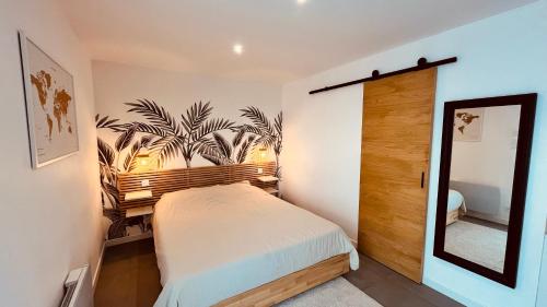 une chambre avec un lit et un miroir dans l'établissement T2 des pins, océan et soleil, à Saint-Jean-de-Monts