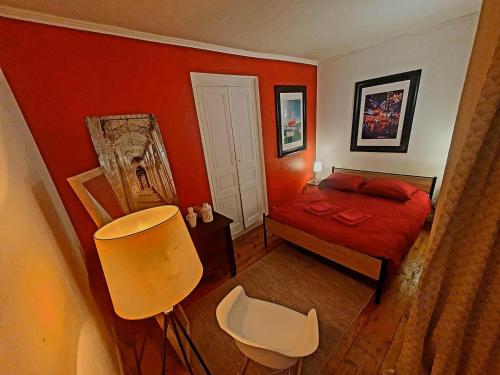 - une chambre avec un lit rouge et une chaise blanche dans l'établissement Chez Jeanne, à Saint-Brieuc