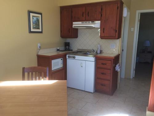 a kitchen with wooden cabinets and a white dishwasher at Hotel-Motel Fleur de Lys in Perce
