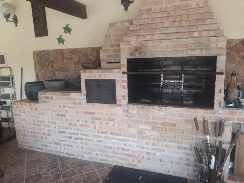 einen gemauerten Kamin in einem Zimmer mit Töpfen und Pfannen in der Unterkunft Casa Alto Padrão Casa Laranja in Praia Sêca