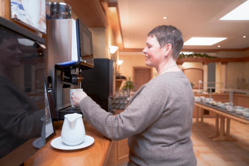 a woman is making a cup of coffee at Gästehaus Kraft in Lauffen am Neckar