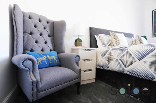 a bedroom with a blue chair next to a bed at Stunning Victorian pub conversion apartment in Lowestoft