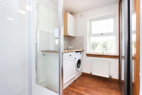 a laundry room with a washing machine and a window at JOIVY Greenknowes Estate with Hot Tub and Bar - Farmhouse and Lodge in Kelty