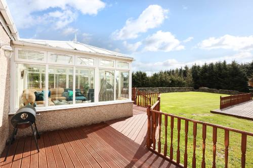 a house with a conservatory on a wooden deck at JOIVY Greenknowes Estate with Hot Tub and Bar - Farmhouse and Lodge in Kelty