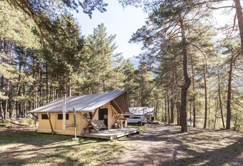 a tent in the woods with a car parked at Huttopia La Clarée in Val-des-Prés