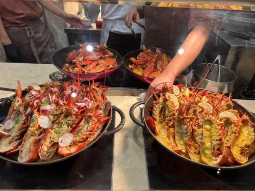 two pans filled with different types of seafood on a counter at Luxury Penthouse & High-Floor Hotel near City of Dreams, Airport, Okada, and Solaire Casino in Manila