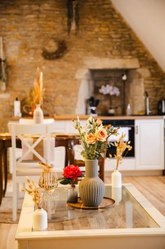 a kitchen with a table with vases of flowers on it at La suite Nacrée - Magnifique Studio in Bernières-sur-Mer