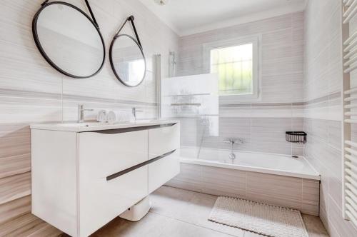 une salle de bain avec un lavabo, une baignoire et un miroir dans l'établissement LEGARREKO BIDEA Beautiful house with a pool between land and sea, à Larressore