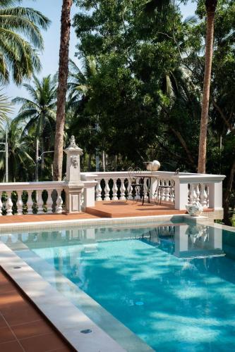 a swimming pool with a white fence and palm trees at O - HO Boutique Home in Baan Tai