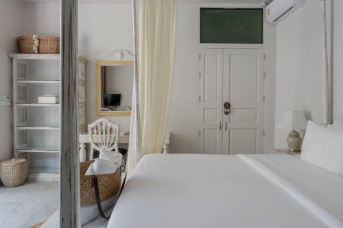 a white bedroom with a bed and a chair at O - HO Boutique Home in Baan Tai