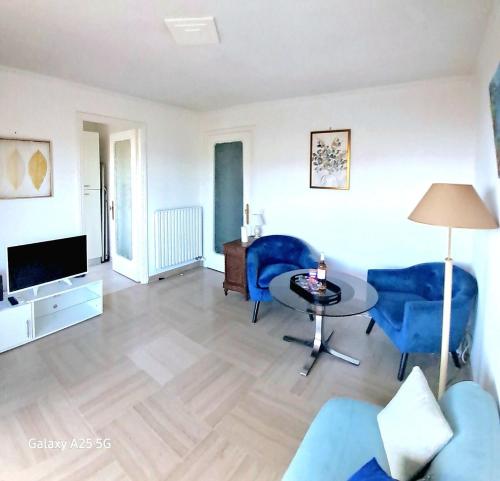 un salon avec des chaises bleues et une table dans l'établissement Appartement au calme aperçu mer et collines 2 personnes, à Cannes