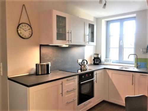 a kitchen with white cabinets and a clock on the wall at Ferienwohnung mit Sauna in Potsdam