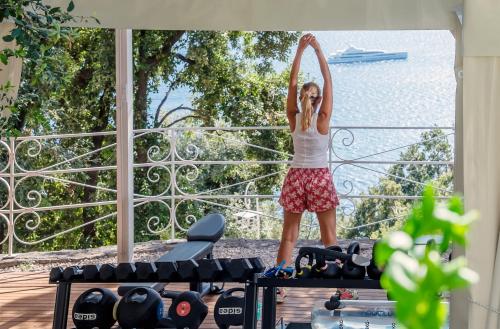 a woman standing on a balcony with her arms in the air at Hotel Piccolo Sant'Andrea in Praiano
