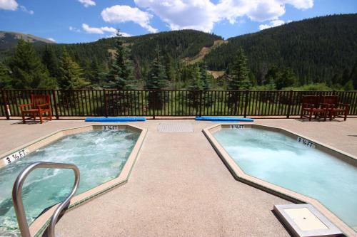 two hot tubs on a patio with mountains in the background at Hidden River Lodge 5981 by SummitCove Lodging in Keystone