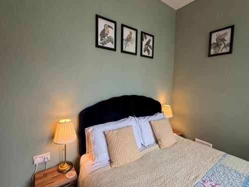 a bedroom with a bed with three pictures on the wall at Hargate Hall Self Catering in Buxton