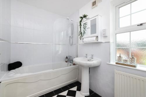 a white bathroom with a sink and a bath tub and a sink at JOIVY Greenknowes Lodge with Hot Tub and Wood Burning Stove in Kelty