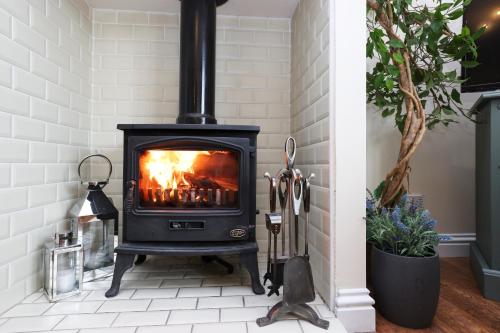 a fireplace in a living room with white tile at JOIVY Greenknowes Lodge with Hot Tub and Wood Burning Stove in Kelty