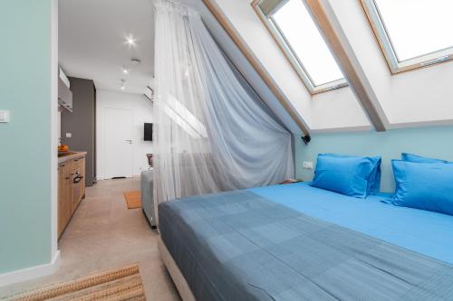a bedroom with a blue bed and windows at Apartamenty Dwie Sosny in Junoszyno