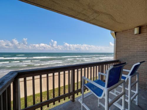 a pair of chairs sitting on a balcony looking at the ocean at Island House BeachFront Condo Hotel in Corpus Christi