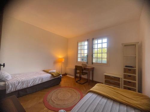 une chambre avec deux lits et un bureau et une fenêtre dans l'établissement Villa Uzès, à Uzès