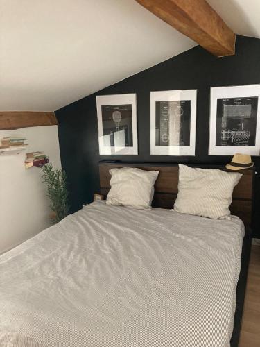 une chambre avec un grand lit avec trois tableaux au mur dans l'établissement Loft Hyper centre Saintes, à Saintes