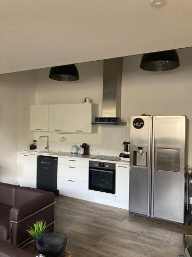 une cuisine avec un réfrigérateur en acier inoxydable et des armoires blanches dans l'établissement Loft Hyper centre Saintes, à Saintes