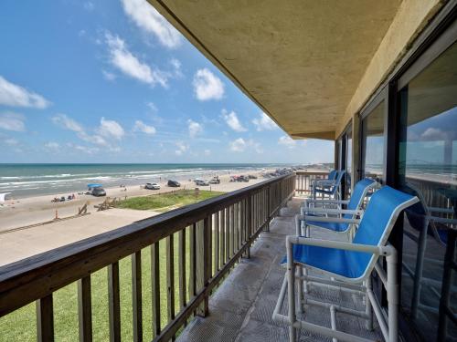 a balcony with blue chairs and a view of the beach at Island House BeachFront Condo Hotel in Corpus Christi