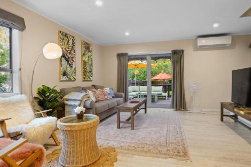 a living room with a couch and a table at Seaside Bougainvillea Retreat close to Beaches in Auckland