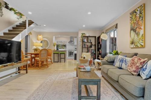 a living room with a couch and a tv at Seaside Bougainvillea Retreat close to Beaches in Auckland