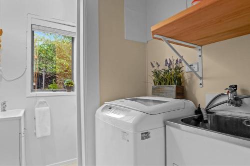 un bagno con lavandino e lavatrice di Seaside Bougainvillea Retreat close to Beaches ad Auckland