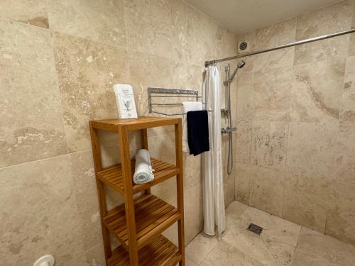 a bathroom with a shower and a wooden shelf with towels at Hargate Hall Self Catering in Buxton
