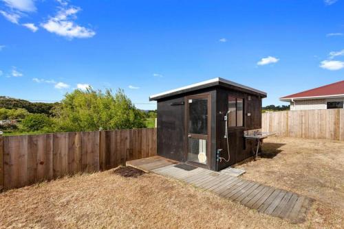 a small black shed in a yard next to a fence at Waiotahe Executive Getaway in Opotiki