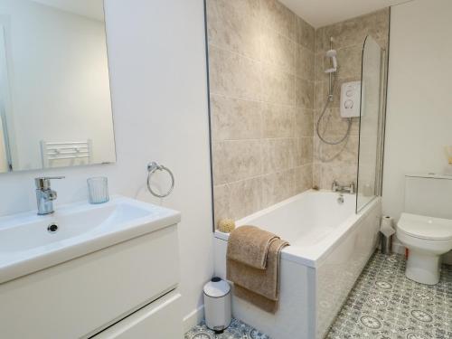a bathroom with a sink and a tub and a toilet at Cornel Clud in Cemaes Bay