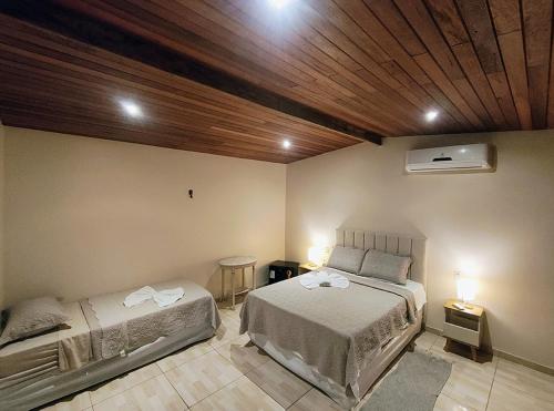 a bedroom with two beds and a wooden ceiling at Pousada AldeiA Cotijuba in Belém