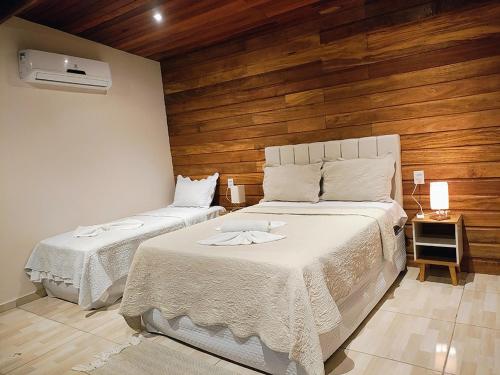 a bedroom with two beds and a wooden wall at Pousada AldeiA Cotijuba in Belém