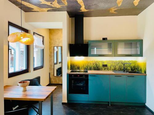 a kitchen with blue cabinets and a wooden table at Deluxe Apartment im Grünen mit Balkon und Frühstück im Hotel Reindahls in Wilkendorf