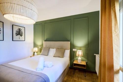 a bedroom with a large white bed with green walls at Azpilagaña by Clabao in Pamplona